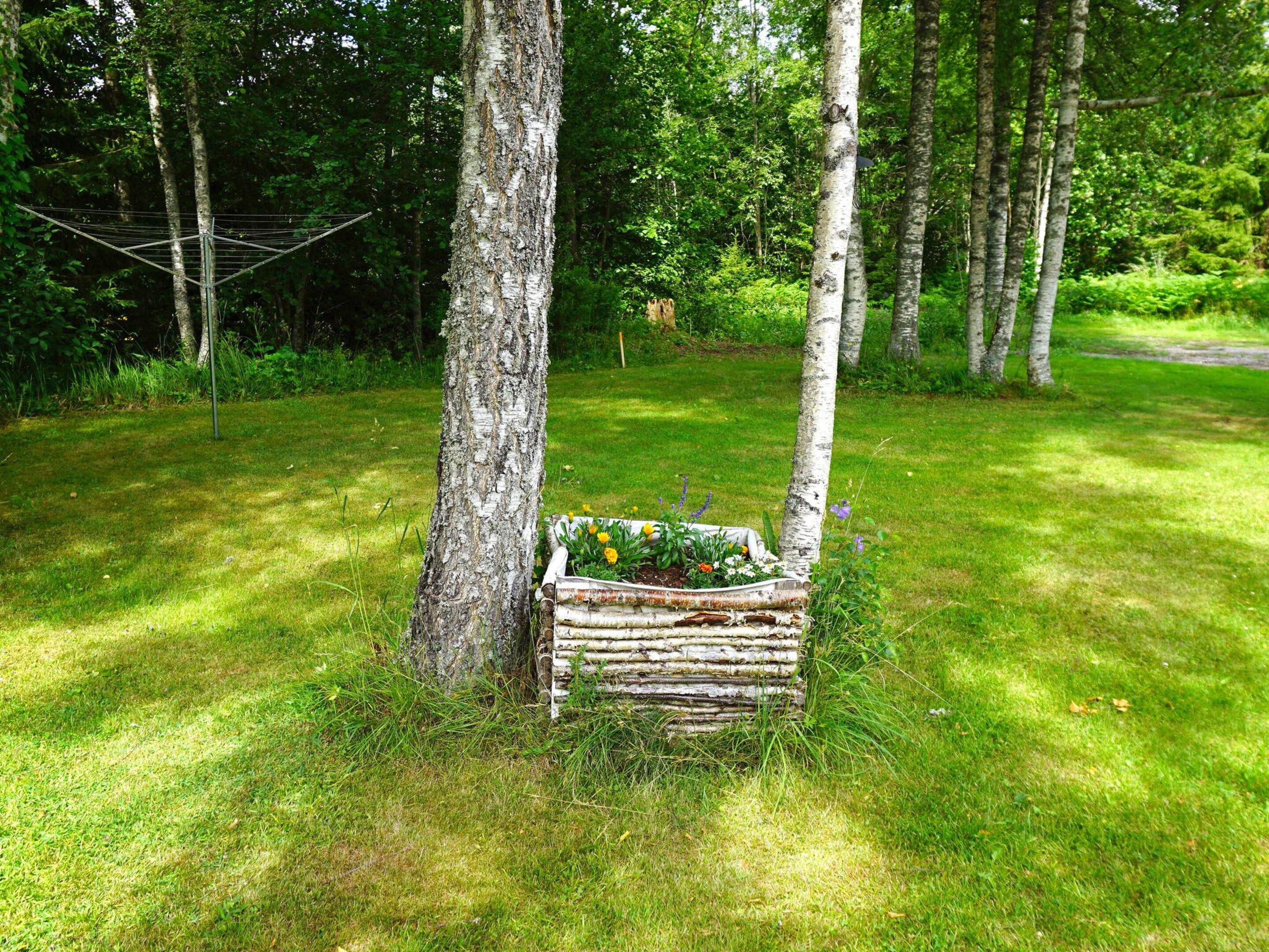 A rustic wooden bench with a floral arrangement in a lush green forest setting.
