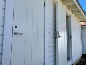 Un bâtiment blanc doté d’une porte coulissante et d’une petite fenêtre.