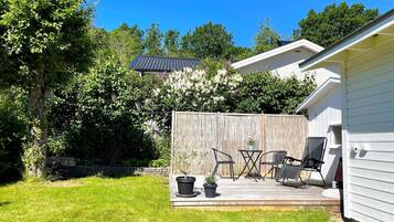 A backyard with a wooden deck, outdoor furniture, and a fenced area.