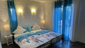 Ein Schlafzimmer mit einem Bett, zwei Nachttischen, einer Fensterbank, Vorhängen und einer Wandleuchte.