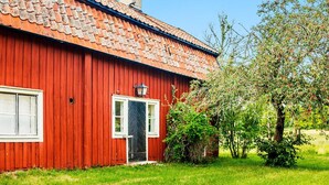 A red wooden house with a tiled roof, a white door, and a small window. - 5 Person Holiday Home in Flen (Flen)