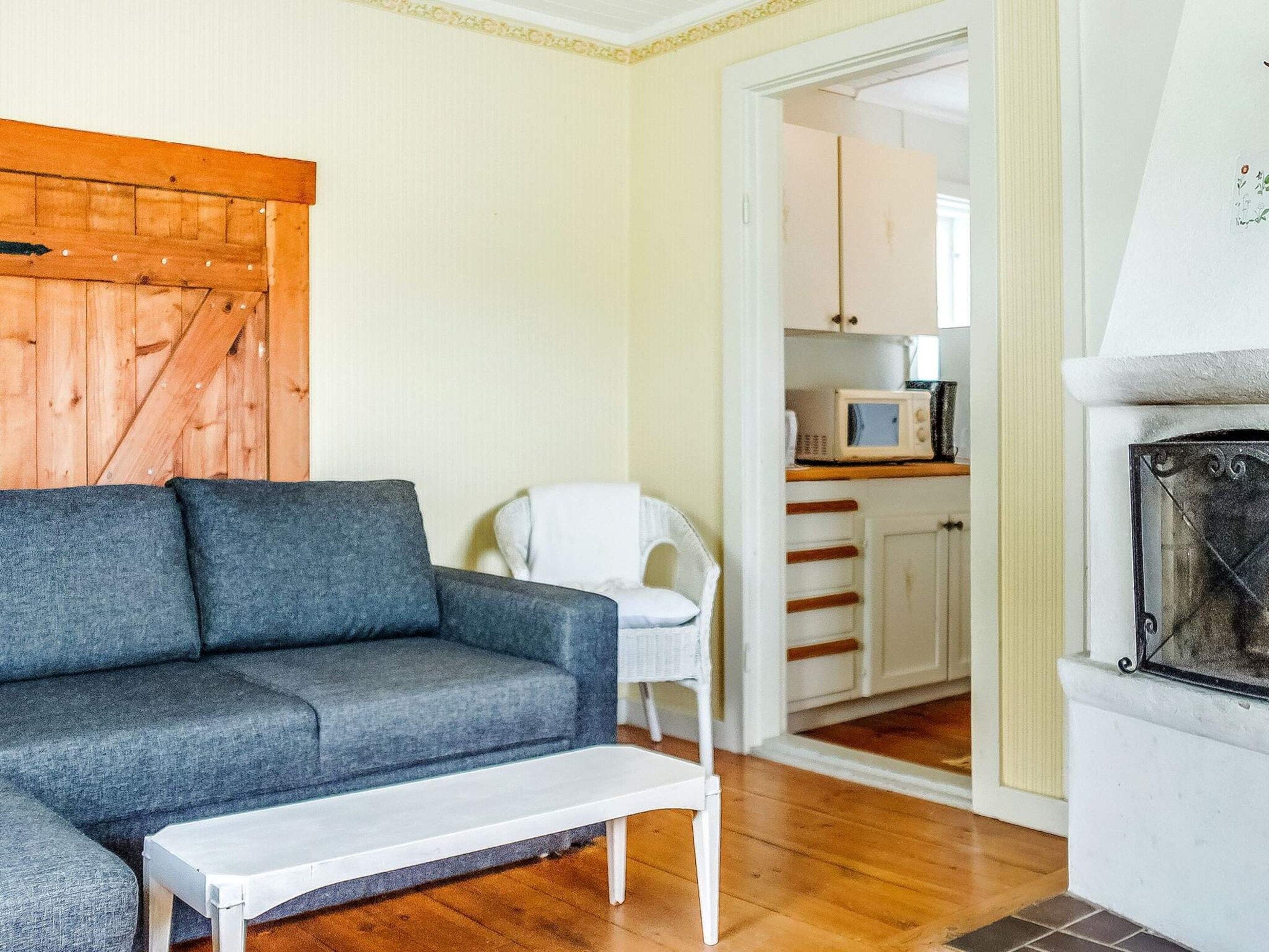 A living room with a grey sofa, a white armchair, a white coffee table, and a wooden door.