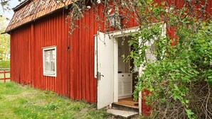 A red wooden building with a white door and a small window. - 5 Person Holiday Home in Flen (Flen)