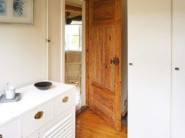 Una habitación con un aparador blanco, una puerta de madera y una silla de mimbre.