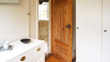 A room with a white dresser, a wooden door, and a wicker chair.