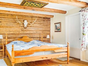 A wooden bed with a headboard, a wall-mounted animal skull, and a framed picture on the wall. - 5 Person Holiday Home in Flen (Flen)