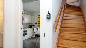Eine Küche mit weißen Schränken, einer Holztreppe und einem roten und gelben Vorhang.