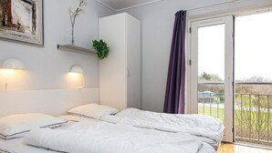 Ein Schlafzimmer mit zwei Betten, einem weißen Kleiderschrank, einem Bild und einer Pflanze auf einem Regal.