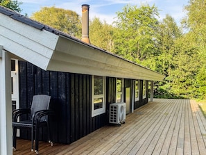 A covered outdoor area with a wooden deck, a black exterior wall, and a chimney. - 6 Person Holiday Home in Hals (Hals)