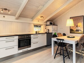 A modern kitchen with white cabinetry, a black countertop, and a dining area with a table and chairs.