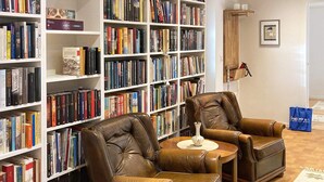 Une pièce comprenant deux fauteuils en cuir, une petite table ronde et une bibliothèque remplie de livres.