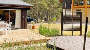 Une maison moderne dotée d’une terrasse, d’un espace salon extérieur abrité et d’une grande fenêtre.
