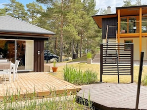 Uma casa moderna com terraço, área de estar coberta ao ar livre e uma grande janela.