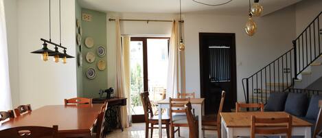 A dining area with a wooden table and chairs, a sewing machine, and a view of the outside.