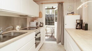A compact kitchen with white cabinets, a stainless steel sink, a microwave, and a coffee maker. - 5 Person Holiday Home in Frederiksvaerk (Frederiksvaerk)