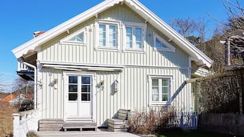 A white two-story house with a front porch, a garage, and a fenced yard.