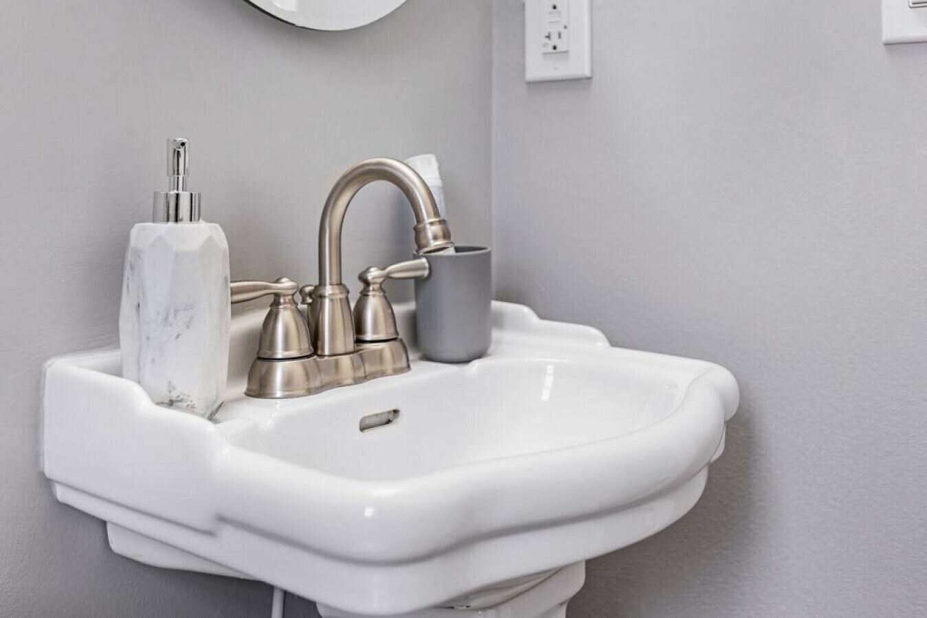 A white bathroom sink with a single faucet and a marble soap holder.