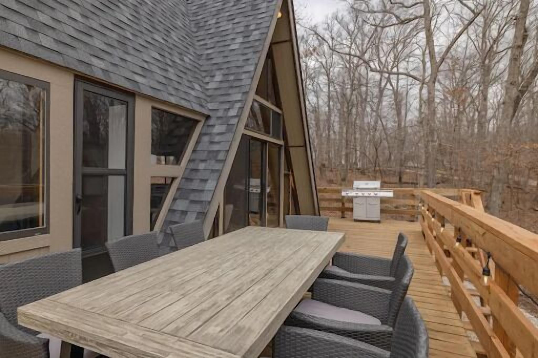 A wooden deck with a dining table and chairs, surrounded by a wooden railing.