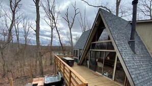 Una cabaña moderna con terraza de madera, ventanas amplias y techo inclinado.