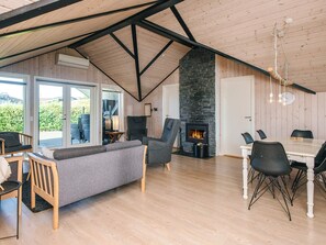 Un loft espacioso con techo alto, chimenea, zona de comedor y sala de estar con sofá y sillones.