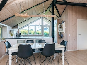 A modern kitchen with a large island, black chairs, and a dining table.
