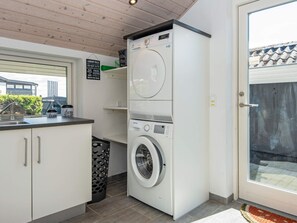 A compact laundry room with a front-loading washing machine, a drying rack, and a sink. - 7 Person Holiday Home in Hejls (Hejls)