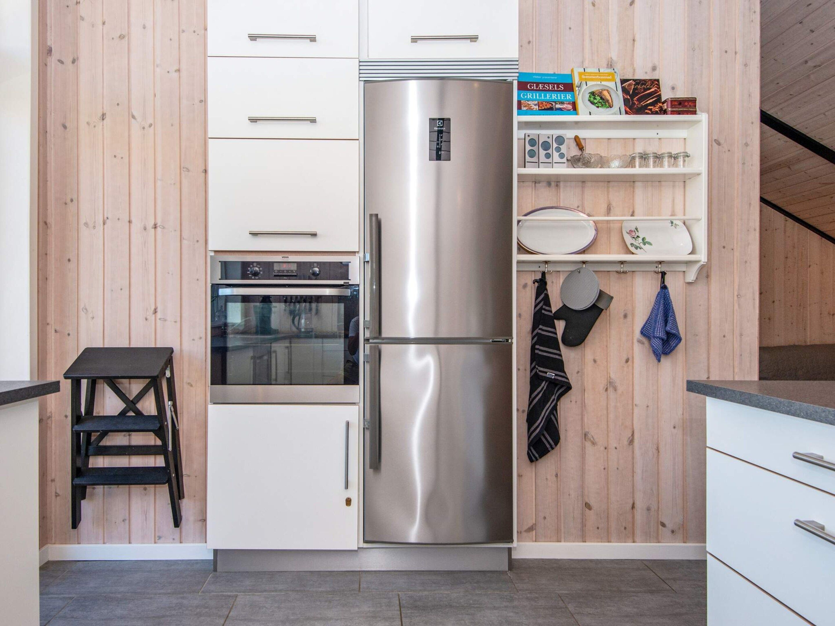 Una cocina moderna con refrigerador de acero inoxidable, horno empotrado y paneles de madera.