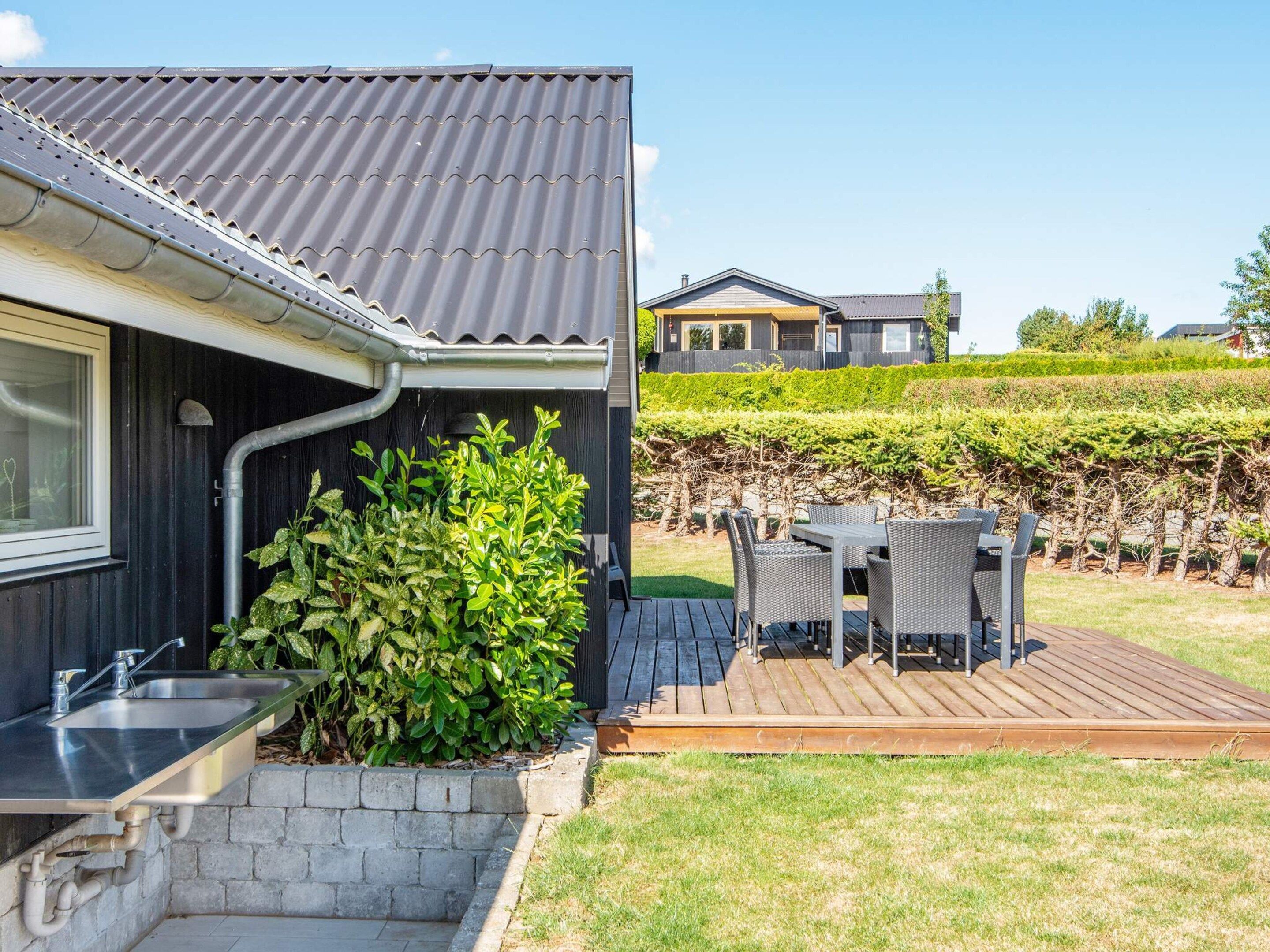 A modern house with a kitchen area, outdoor seating, and a garden.
