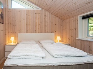 A double bed with two bedside tables, each with a lamp, in a room with wooden panel walls and a sloped ceiling. - 7 Person Holiday Home in Hejls (Hejls)