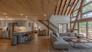 Een ruime zithoek met een houten plafond, een grote bank, een bijzettafeltje en uitzicht op de omgeving.