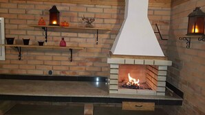A brick fireplace with a white hood, shelves with pumpkins and lanterns, and a wooden bench.
