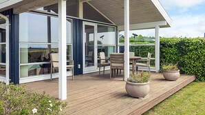 A modern house with a covered patio, large windows, and outdoor seating. - 6 Person Holiday Home in Karrebaeksminde (Karrebæksminde)