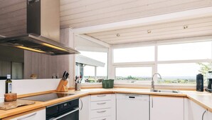 A modern kitchen with a dishwasher, oven, and a large window offering a view of the outdoors. - 6 Person Holiday Home in Karrebaeksminde (Karrebæksminde)