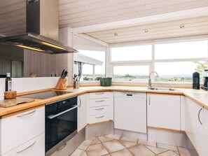 A modern kitchen with a dishwasher, oven, and a large window offering a view of the outdoors. - 6 Person Holiday Home in Karrebaeksminde (Karrebæksminde)