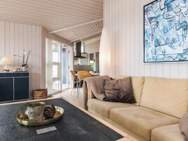 A living room with a sofa, a coffee table, and a dining area with chairs and a table.