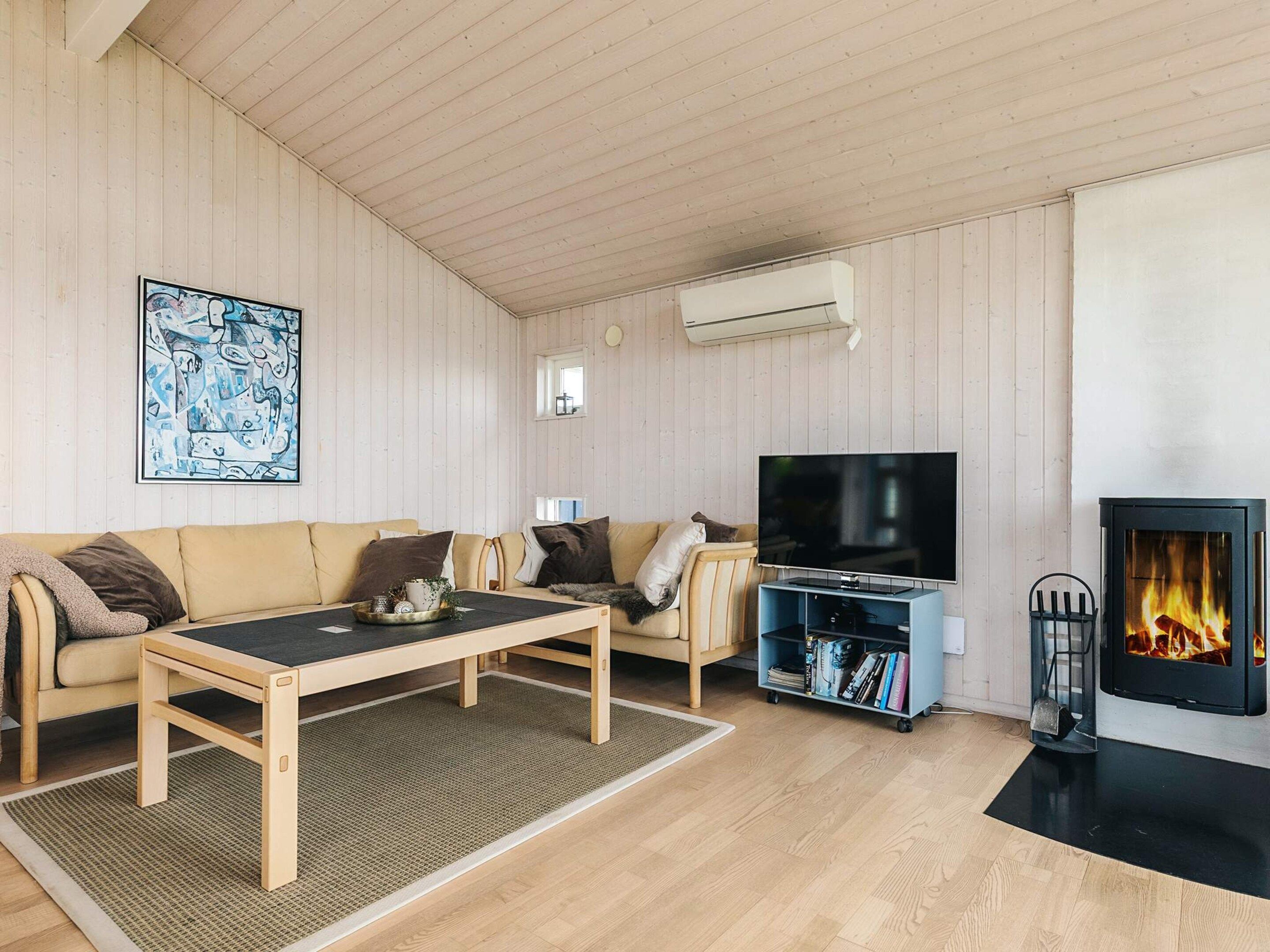 A cozy living room with a sofa, a coffee table, a flat-screen TV, a bookshelf, and a fireplace.