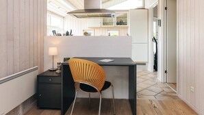 A modern kitchen with a wooden floor, a black countertop, a wooden chair, and a built-in stove. - 6 Person Holiday Home in Karrebaeksminde (Karrebæksminde)