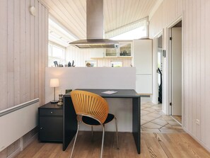 A modern kitchen with a wooden floor, a black countertop, a wooden chair, and a built-in stove. - 6 Person Holiday Home in Karrebaeksminde (Karrebæksminde)