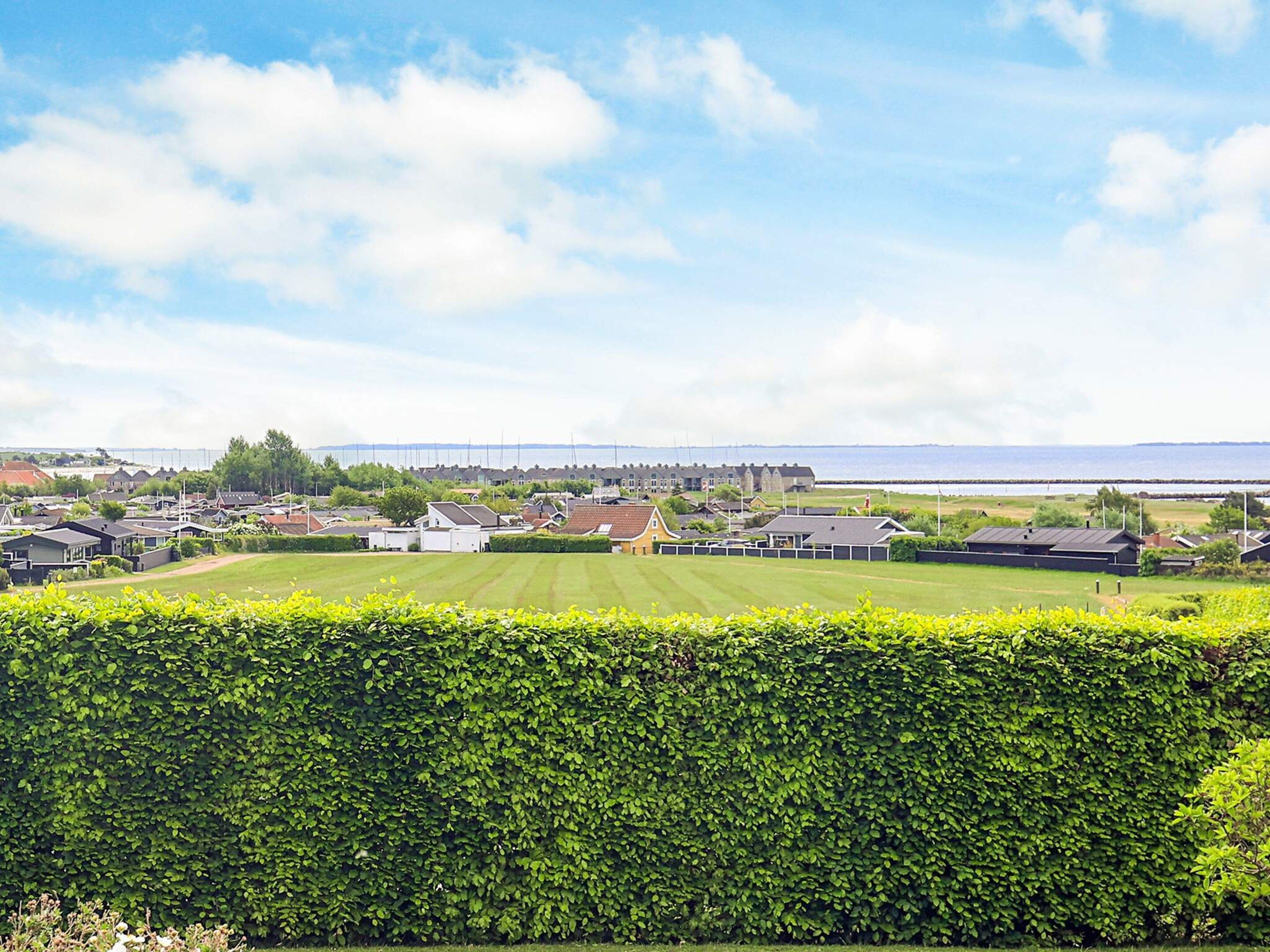 Un quartier résidentiel avec des maisons, une pelouse bien entretenue et une haie au premier plan.