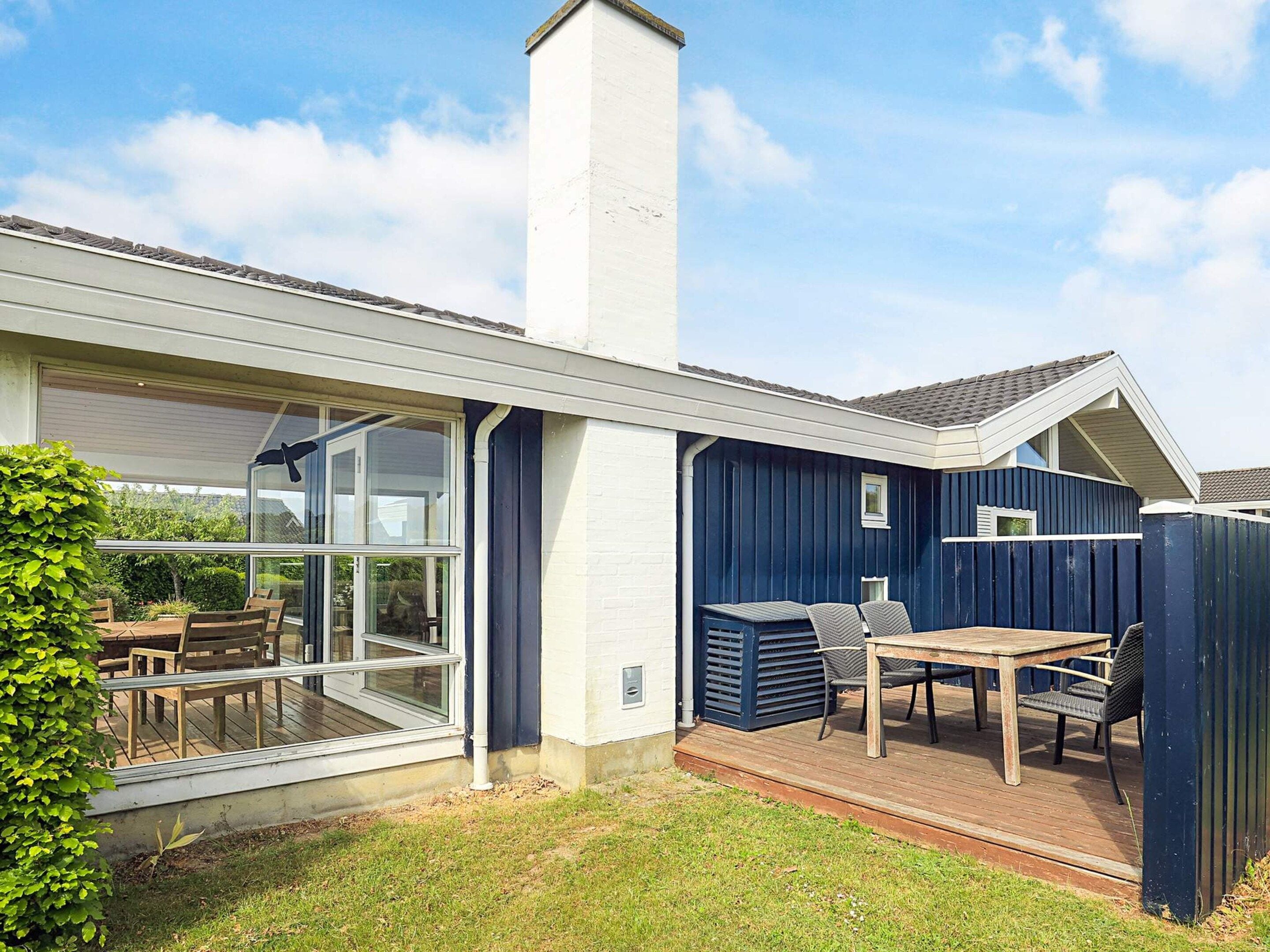 A residential property with a covered patio, a large window, and a chimney.