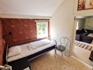 Ein Schlafzimmer mit einem Einzelbett, einem Sessel und einem Fenster.