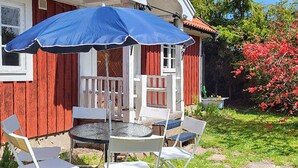 An outdoor seating area with a table and chairs, a grill, and a blue umbrella. - 5 Person Holiday Home in Haltorp (Halltorp)