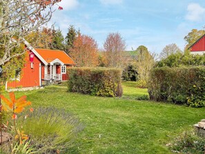 A red building with a white porch and a green lawn.