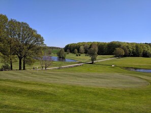 A golf course with a pond, trees, and a clear sky. - 5 Person Holiday Home in Haltorp (Halltorp)