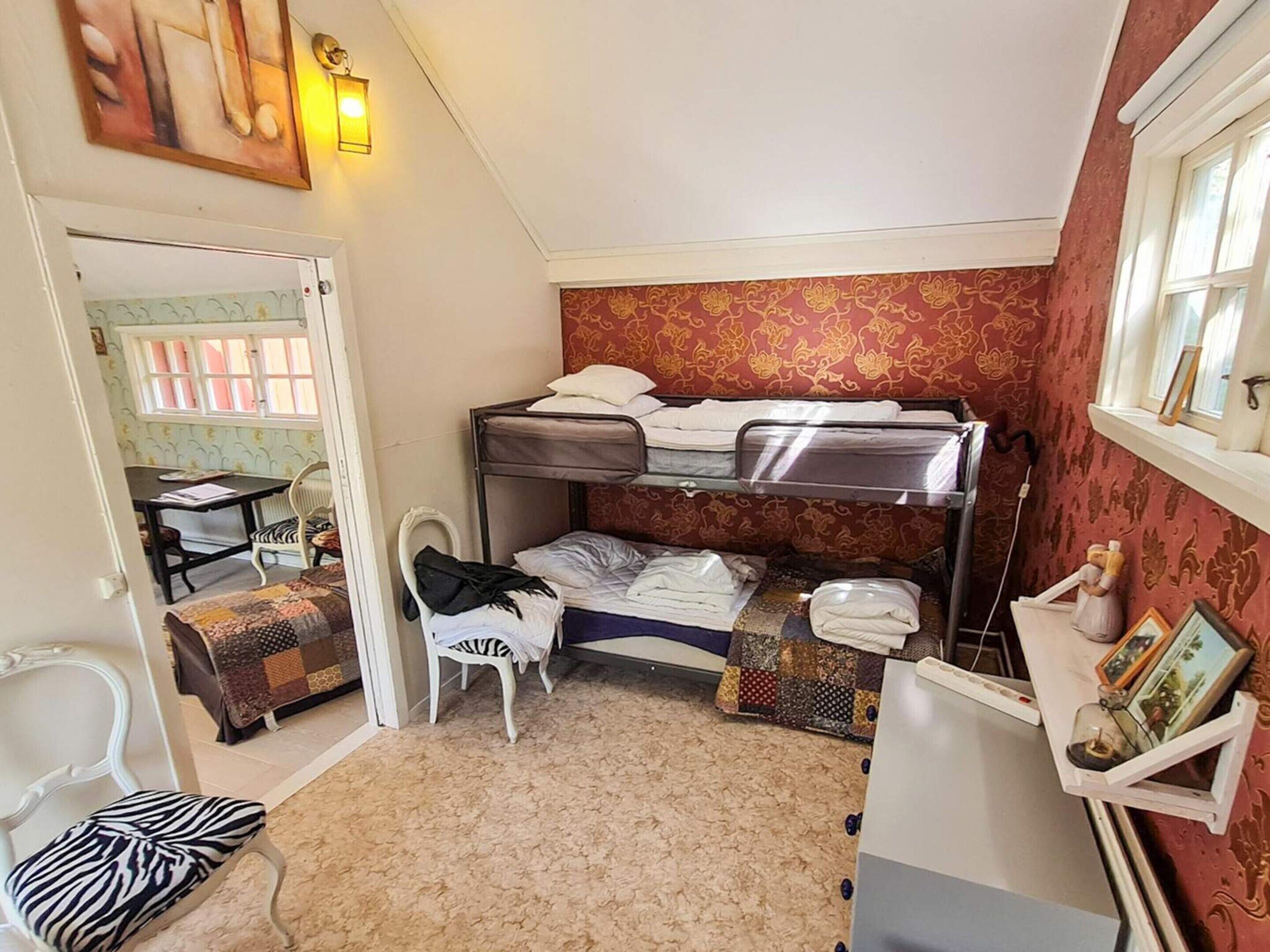 A compact room with bunk beds, a small table, a chair, and a radiator.