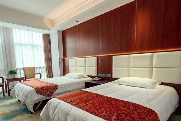 Quarto de hotel com duas camas, cabeceira de madeira, uma escrivaninha e uma cadeira.