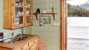 A wooden kitchen with a wooden counter, cabinets, and a small shelf with bottles. - 8 Person Holiday Home in Orskog (Ålesund)