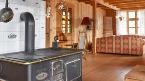 A traditional wooden interior with a vintage stove, wooden furniture, and a large window. - 8 Person Holiday Home in Orskog (Ålesund)