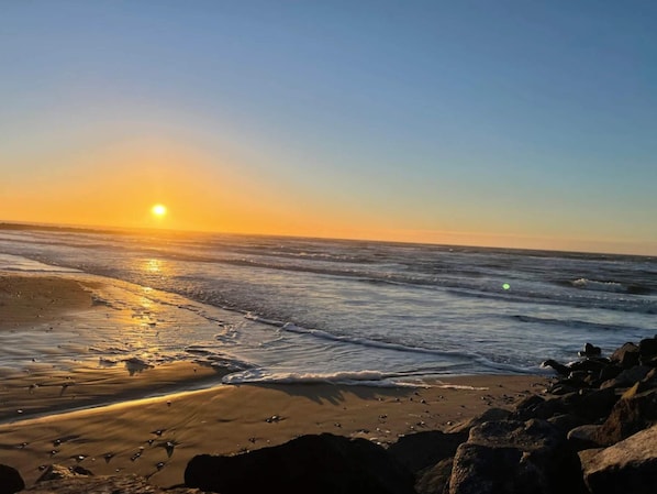 A beach with waves, a clear sky, and the sun setting or rising. - 4 Star Holiday Home in Hjorring (Hjørring)