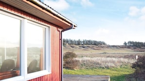 Punainen rakennus, jossa on suuret ikkunat ja puinen terassi.